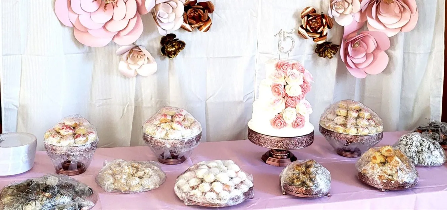 A Rosa's dessert table with cookies, pastries, and a cake