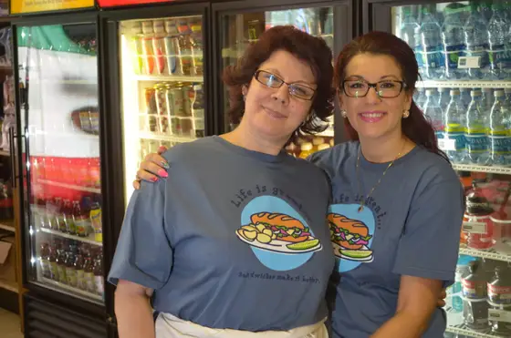 Rosa and Sonia in matching Rosa's T-shirts in front of the drink coolers